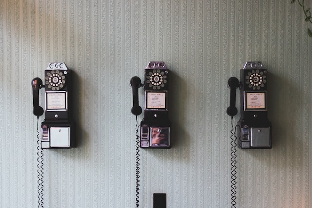 three rotary-dial phones side by side