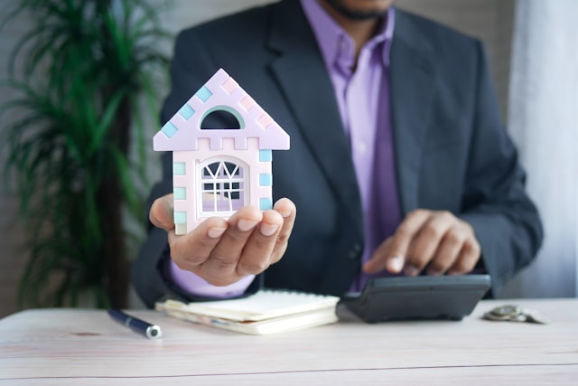 person in suit holding foam toy house