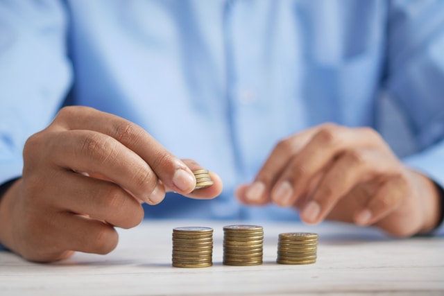 person putting coins on a stack