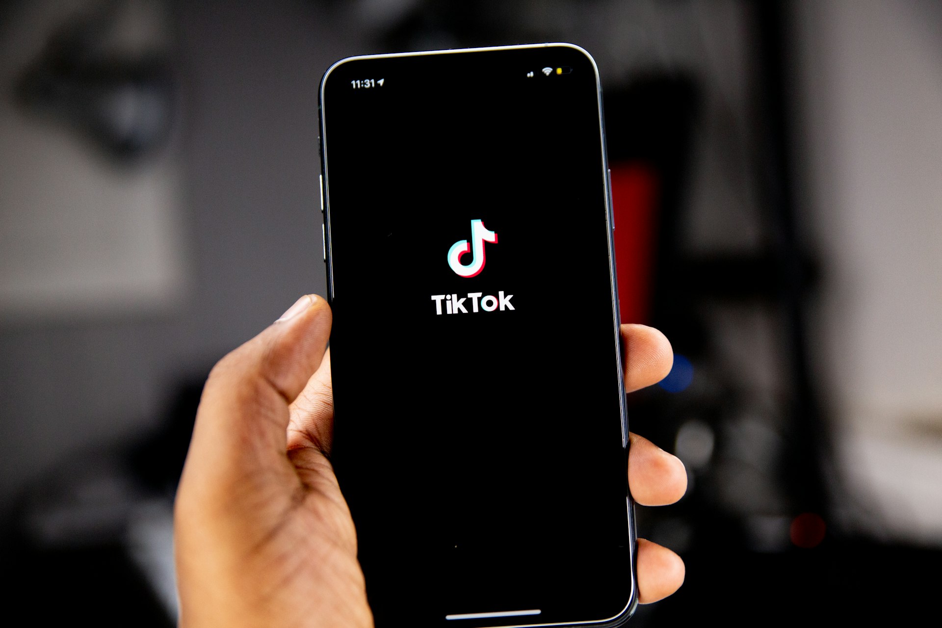 A hand holding a smartphone showing the TikTok logo